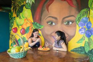 two young girls sitting at a table in front of a mural at Hostel Travelers Santiago in Santiago