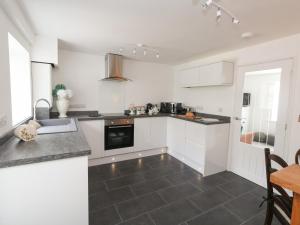 a kitchen with white cabinets and a black tile floor at 5 Coastguard Cottage in Portland