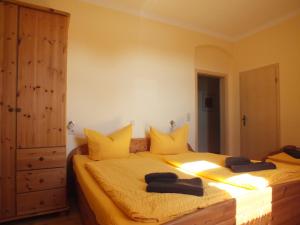 ラーデボイルにあるPension am Elberadwegのベッドルーム1室(黄色いシーツとドレッサー付きのベッド2台付)