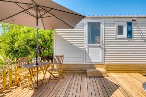 a wooden deck with an umbrella and a table and chairs at Casa Amarelo-Tiny House with fantastic view-pool and close to the beaches in Silves