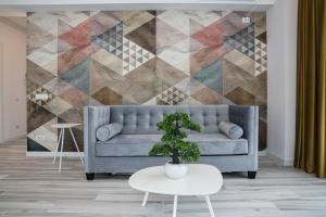 uma sala de estar com um sofá azul e uma parede geométrica em Bel Air Apartments Mamaia Nord em Mamaia