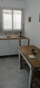 a kitchen with white cabinets and a wooden table at Apartamento junto al Peñon de Ifach con parking in Calpe
