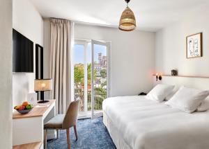 Pokój hotelowy z łóżkiem, biurkiem i oknem w obiekcie Hotel Le Suquet Cannes w Cannes