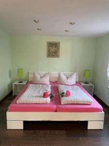 Una cama grande con sábanas rosas y flores. en Rosental, en Stollberg