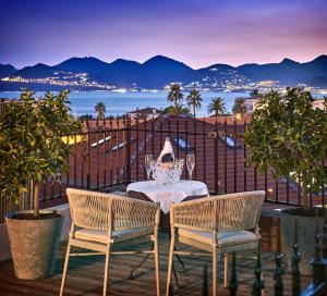 uma mesa e cadeiras numa varanda com vista para o oceano em Hotel Le Suquet Cannes em Cannes