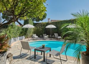 um pátio com uma mesa e cadeiras e uma piscina em Hotel Le Suquet Cannes em Cannes