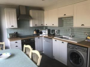 uma cozinha com armários brancos, um lavatório e uma máquina de lavar louça em Lovely 3-Bed Cottage in Brancaster Staithe em Brancaster