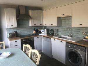 a kitchen with white cabinets and a sink and a dishwasher at A cozy cottage on the North Norfolk coast in Brancaster