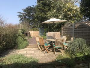 a patio with a table and chairs under an umbrella at A cozy cottage on the North Norfolk coast in Brancaster