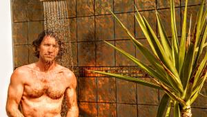 a man standing in a shower next to a plant at Ethereal Apartments in Agrari +43 photos