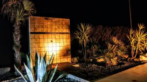 un mur en briques avec une lumière dans un jardin la nuit dans l'établissement Ethereal Apartments, à Agrari