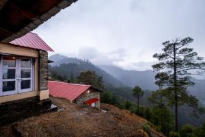 a house with a red roof on top of a mountain at Himalayan Paradise, Boutique room w Binsar view by Roamhome in Almora