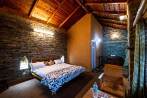 a bedroom with a bed in a brick wall at Himalayan Paradise, Boutique room w Binsar view by Roamhome in Almora