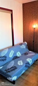 ein Schlafzimmer mit einem Bett mit einer blauen Tagesdecke mit Pflanzen in der Unterkunft STUDIO hyper-centre de LIMOGES in Limoges