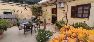 un patio con tavolo, sedie e fiori di House Klimataria Kamilari a Kamilari
