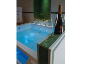 eine Badewanne mit einer Flasche Wein daneben in der Unterkunft Le coccole luxury Suite in Sannicandro di Bari
