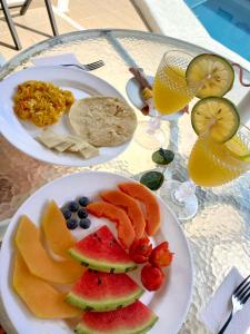 dos platos de fruta en una mesa con vasos de zumo en Hotel Corozal Plaza, en Corozal