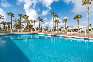 a large swimming pool with palm trees in the background at Jardin del Sol 30 in Playa Blanca