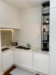 - une cuisine blanche avec des placards blancs et une étagère dans l'établissement Modern Studio in the Historic Center of Bica, à Lisbonne