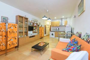 sala de estar con sofá naranja y cocina en Estudio La Colina, en Torremolinos