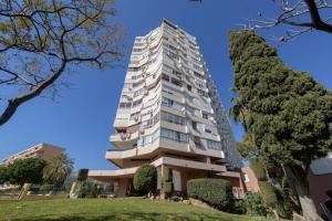 un edificio de apartamentos alto con un árbol en Estudio La Colina, en Torremolinos