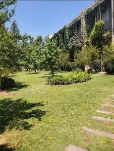 un patio verde con un edificio y árboles y plantas en pilar tortugas departamento premiun en Pilar