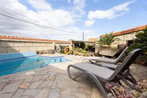 un patio con una silla junto a una piscina en Live Casa Rural El Cango en La Degollada