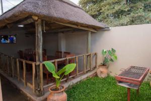 a restaurant with a thatch roof and a table and chairs at 848 Guest House in Victoria Falls