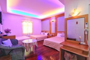a purple room with two beds and a tv at 龍坑民宿 in Eluan
