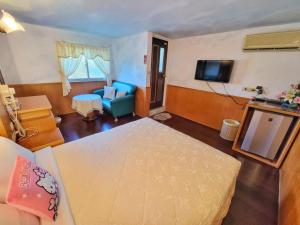 a room with a bed and a couch and a television at 龍坑民宿 in Eluan