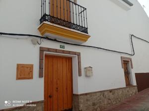 a building with a wooden door and a balcony at La Posada Vivienda Turística Rural in Algar