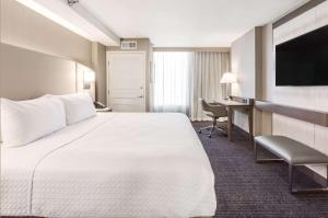 デンバーにあるSonesta Denver Downtownの大きなベッドとデスクが備わるホテルルームです。