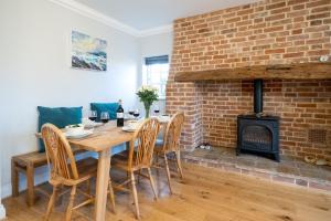 a dining room with a brick fireplace and a table and chairs at 15 Mill Field - Aldeburgh Coastal Cottages in Aldeburgh