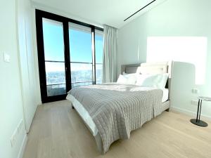 a white bedroom with a large bed and large windows at ICON - Private Holiday Apartments in Limassol