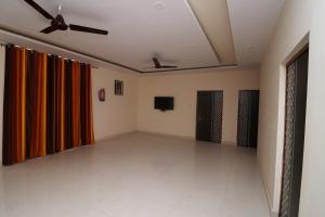 een lege kamer met oranje gordijnen en een tv bij OYO Flagship 27941 Sangam Darshan in Naini