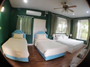 2 Betten in einem Zimmer mit grünen Wänden und einem Spiegel in der Unterkunft Khaoyai Nature Retreat in Baan Wang Mi