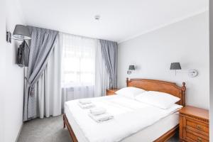 1 dormitorio con 1 cama con sábanas blancas y ventana en Hotel Pod Złotą Różą en Kielce