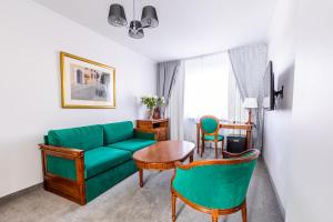 uma sala de estar com um sofá verde e cadeiras em Hotel Pod Złotą Różą em Kielce