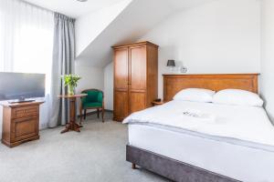 a bedroom with a bed and a flat screen tv at Hotel Pod Złotą Różą in Kielce