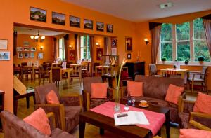 a restaurant with orange walls and tables and chairs at Hotel Habichtstein in Alexisbad