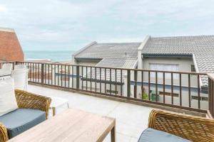 a balcony with chairs and a table and the ocean at Beach front, two story condo in Ballito