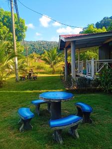 a picnic table and benches in front of a house at Juara Cottage in Tioman Island