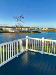 a wooden deck with a white fence and water at Haven Haggerston castle caravan hire in Cheswick