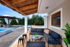 a patio with a blue couch and chairs and a table at Aileen Villa in Koskinou