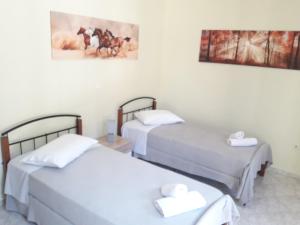 two beds in a room with white sheets and towels at Dourios Ippos Apartments in Frikes