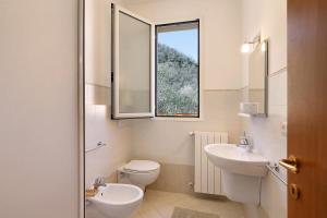 Un baño con inodoro, lavabo y ventana. en Appartamento Ferla La Taggiasca, en Stellanello