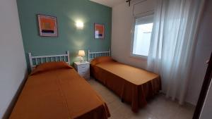 two twin beds in a room with a window at Mar i Angels Apartament in Pineda de Mar