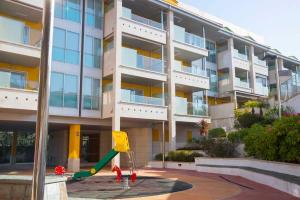 a large apartment building with a playground in front of it at Apartamento Welcome Portonovo Playa in Sanxenxo