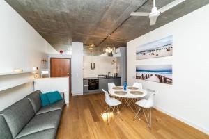 a living room with a couch and a table and chairs at Tarasowy - Neptun Park by OneApartments in Gdańsk