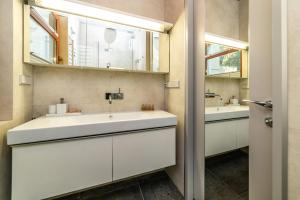 ein Badezimmer mit einem weißen Waschbecken und einem Spiegel in der Unterkunft Tarasowy - Neptun Park by OneApartments in Danzig